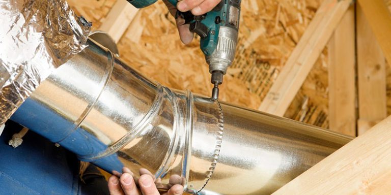 A person using an electric drill to install the pipe.